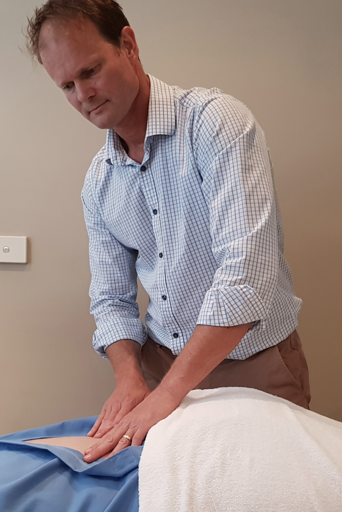 Chiropractor performing assessment on persons lower back