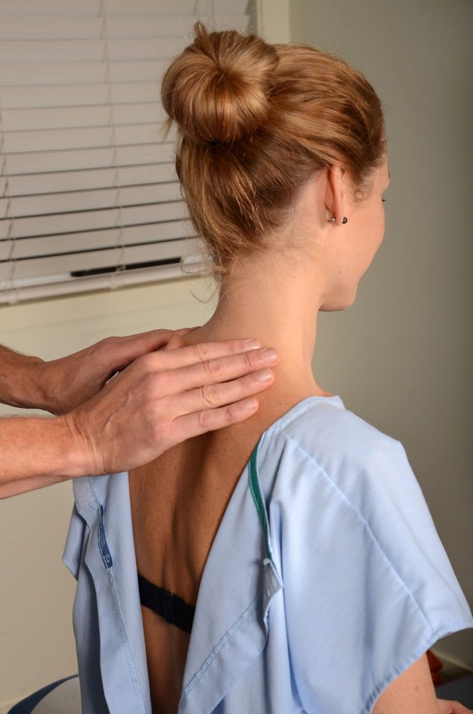 Chiropractor assessing woman's lower neck