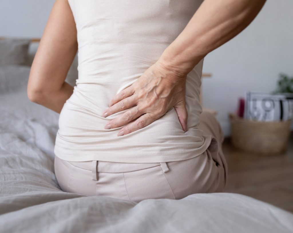 Woman reaching for her lower back while she experiences pain